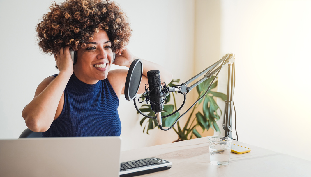 African host woman recording podcast at home studio - Business, podcaster technology - Focus on microphone